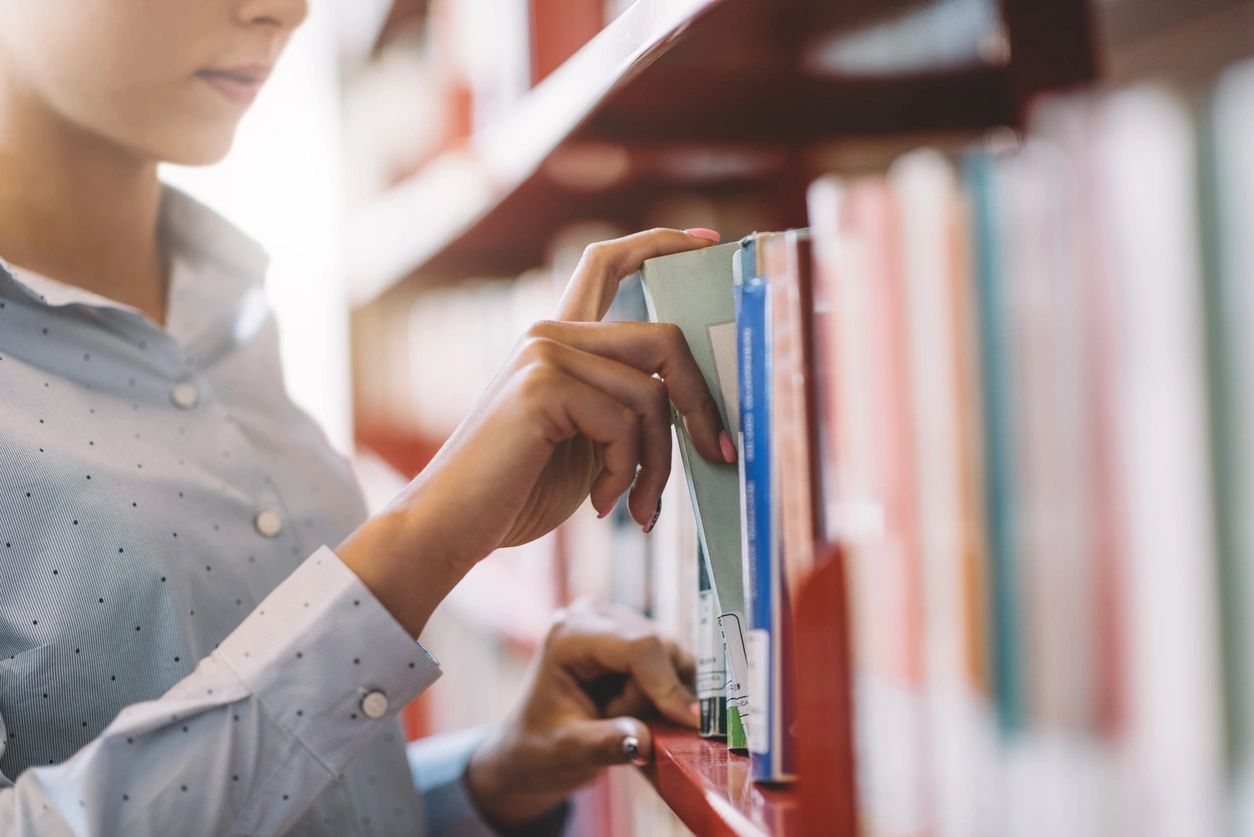 A person is looking at books in the library.