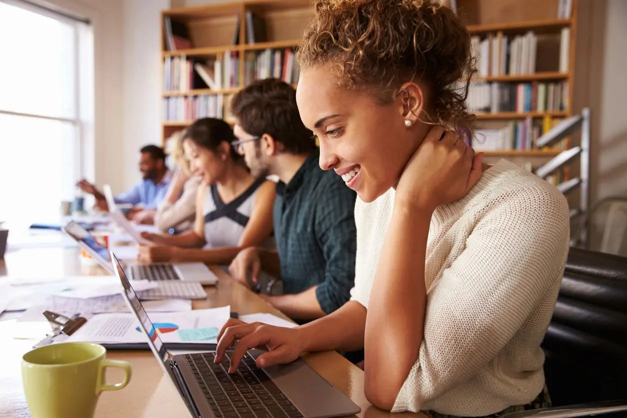 A group of people sitting at tables with laptops.